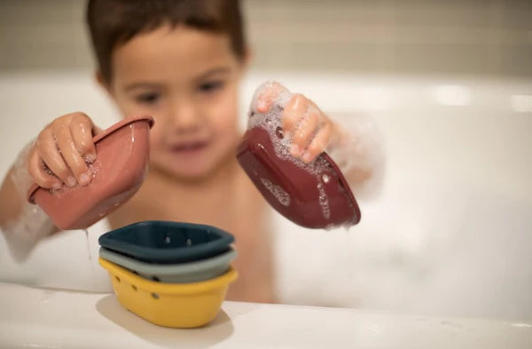 Bébé dans le bain avec Bateaux flottants empilables en silicone bleu, jaune, rouge