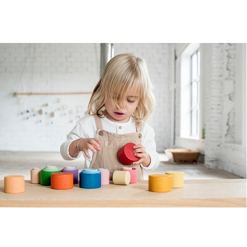 Enfant avec Bols en bois colorés à empiler mauve, bleu, vert, jaune, orange, rouge