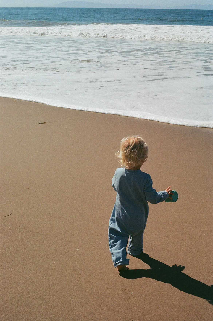 Bébé  à la plage avec Combinaison denim bleu clair