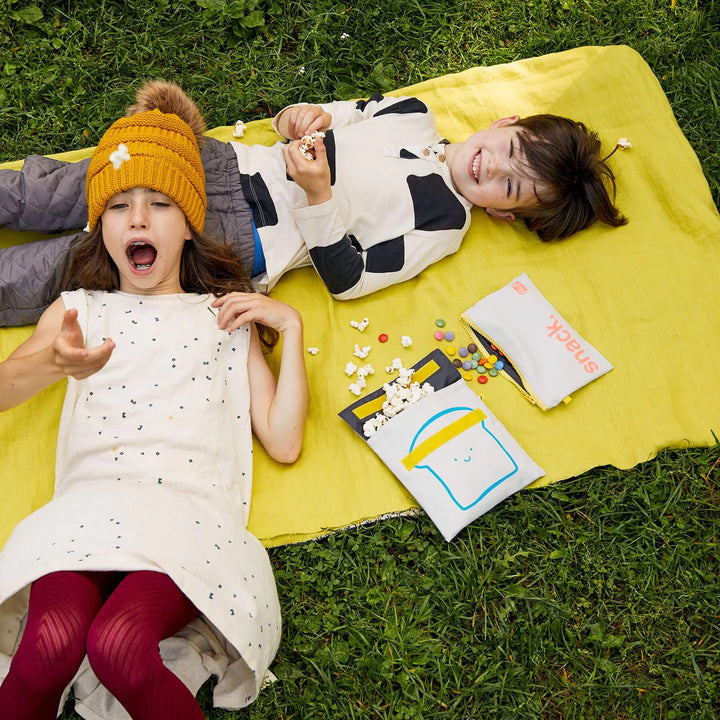 Enfants dans un parc avec Sac à collation en coton bio gris pâle avec imprimé pain bleu