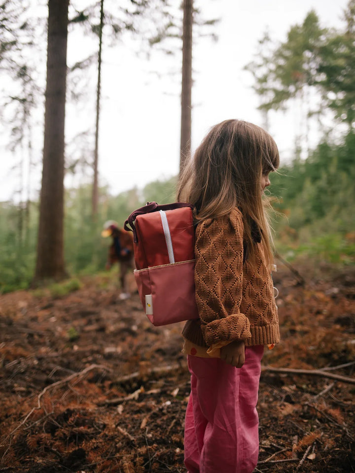 Enfant dans les bois avec Sac à dos fait en bouteilles PET recyclées rouge et rose