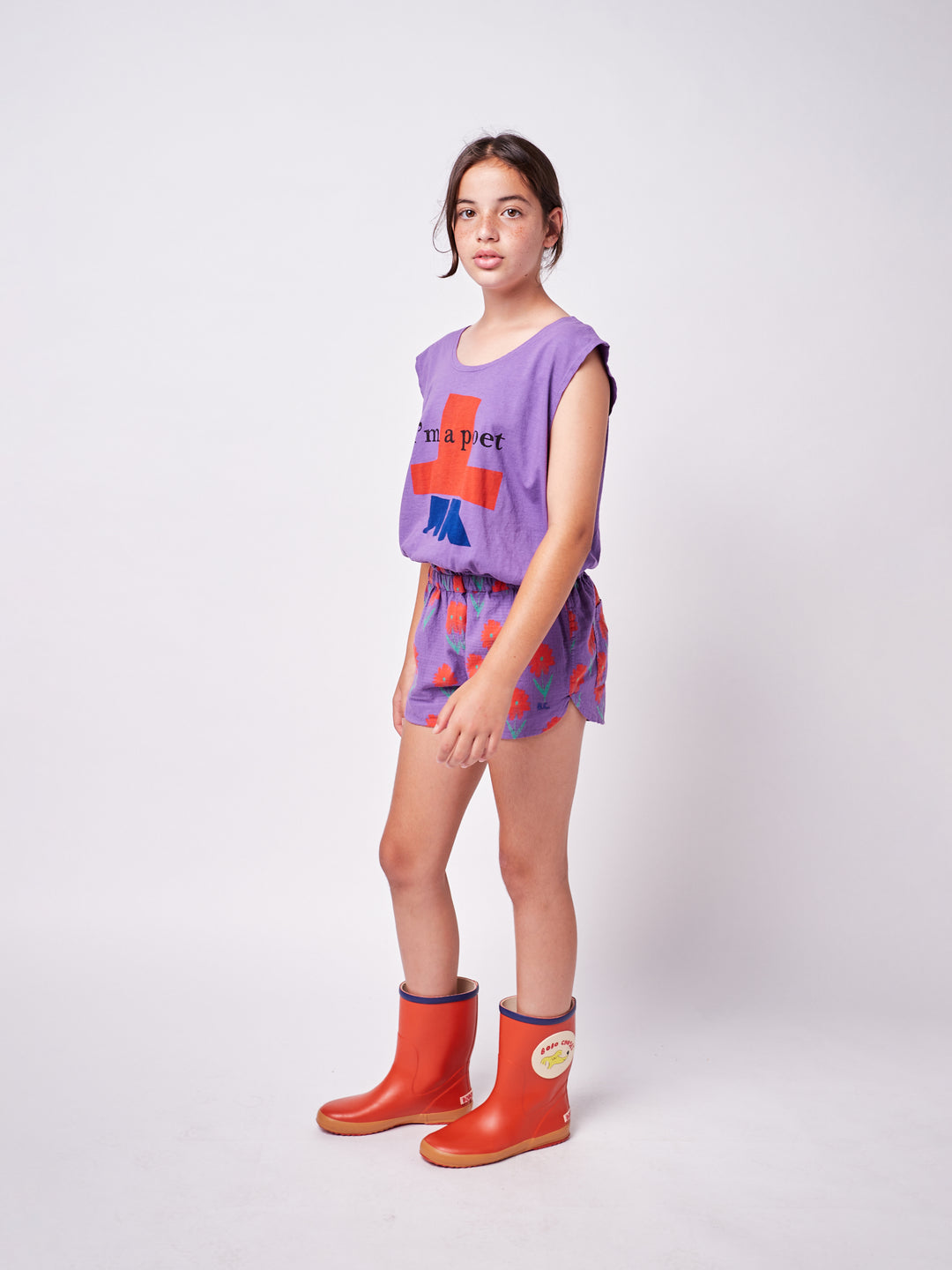 little girl posing wearing colorful printed pants and purple boxy tank top with graphic print and ''I'm a poet'' text