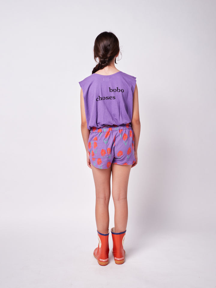 little girl posing from the back wearing colorful printed pants and purple boxy tank top with graphic print and ''Bobo Choses'' text