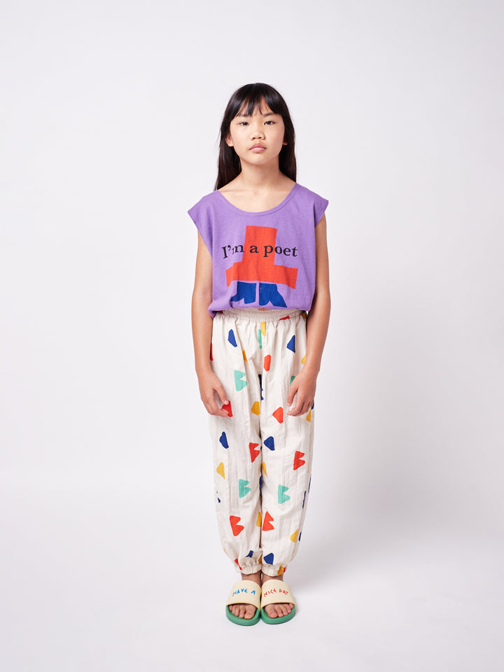 little girl posing wearing colorful printed pants and purple boxy tank top with graphic print and ''I'm a poet'' text