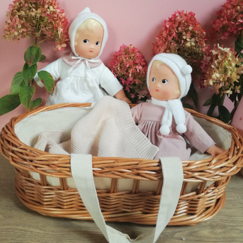 dolls in a floral background with small wicker basket